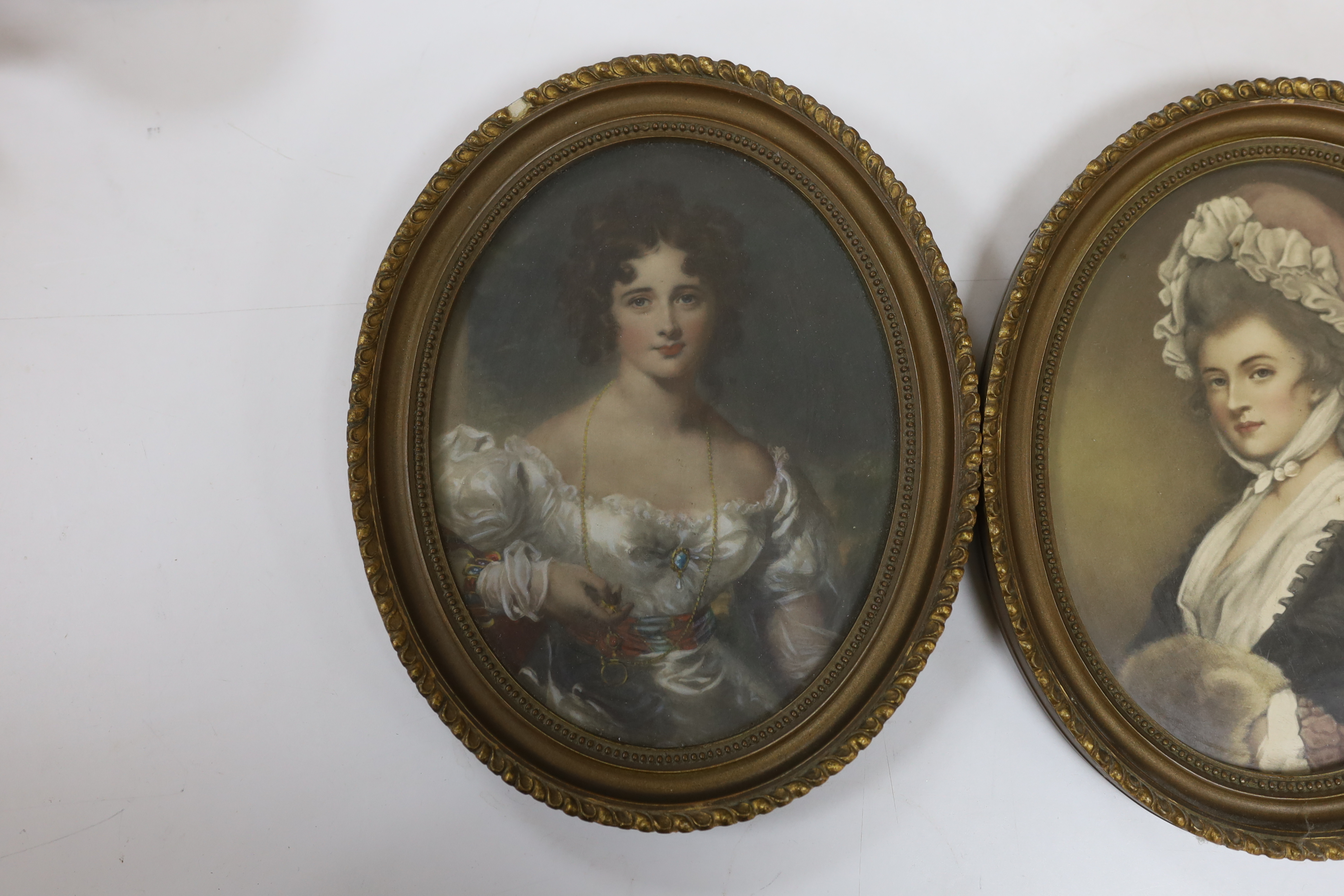 A pair of oval overpainted prints, ladies wearing Georgian dress, gilt framed, 22 x 16cm